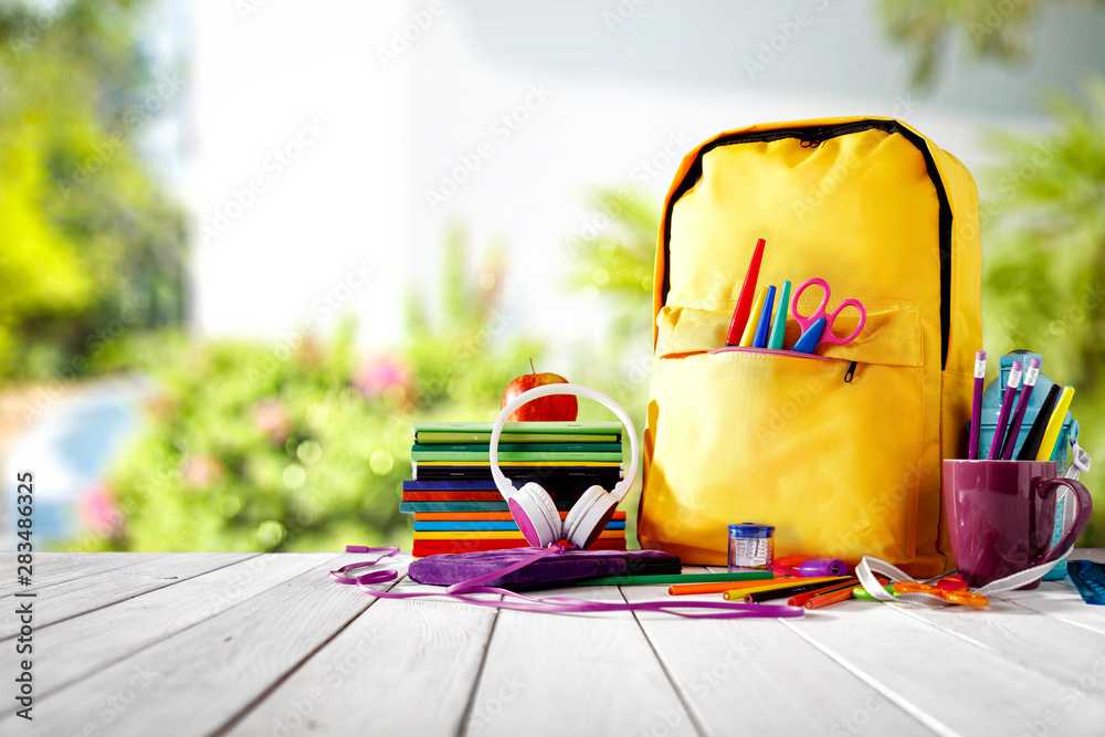 Table background and a schoolbag with some colorful school supplies. Empty space for advertising products and decoration. - obrazy, fototapety, plakaty 