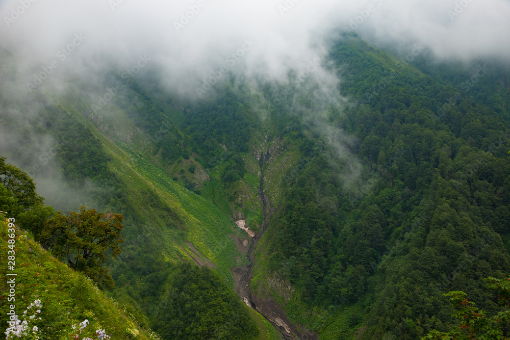 Clouds lie on the green mountain slopes of Omalo, Tusheti, Georgia
