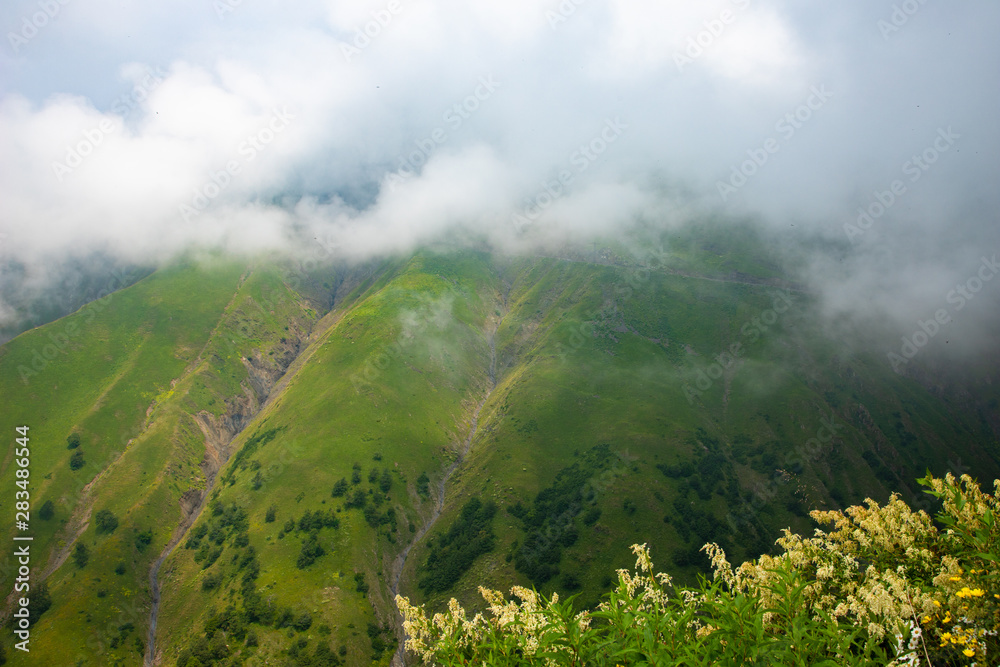 Clouds lie on the green mountain slopes of Omalo, Tusheti, Georgia