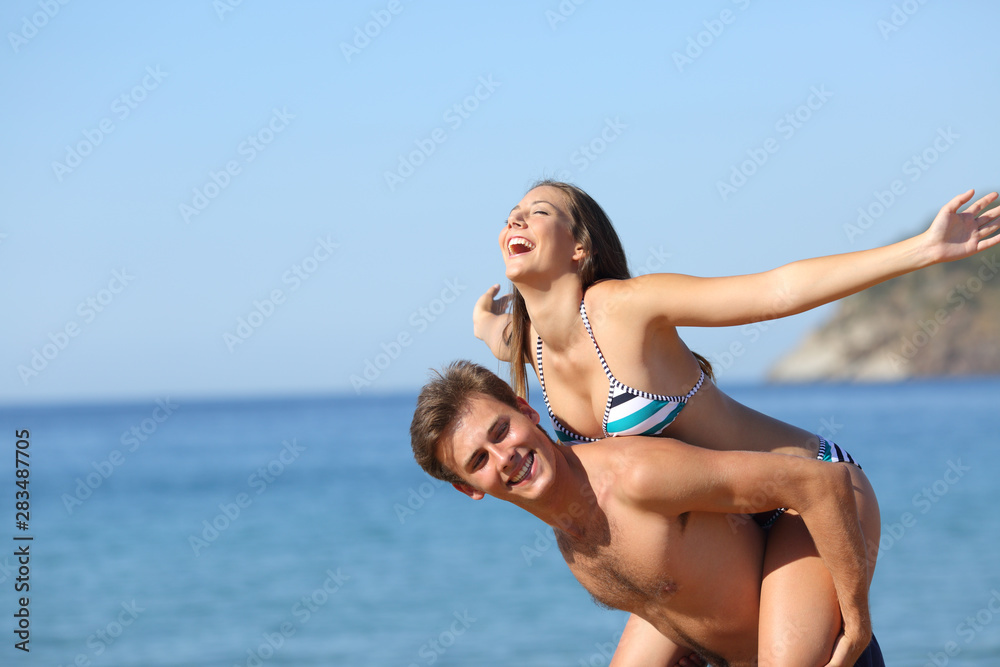 Happy couple joking celebrating vacation on the beach