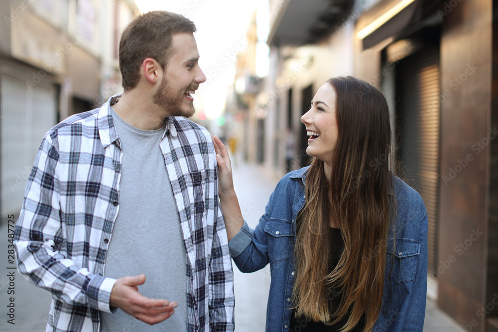 Happy friends flirting walking towards you in the street Happy friends flirting walking towards you in the street
