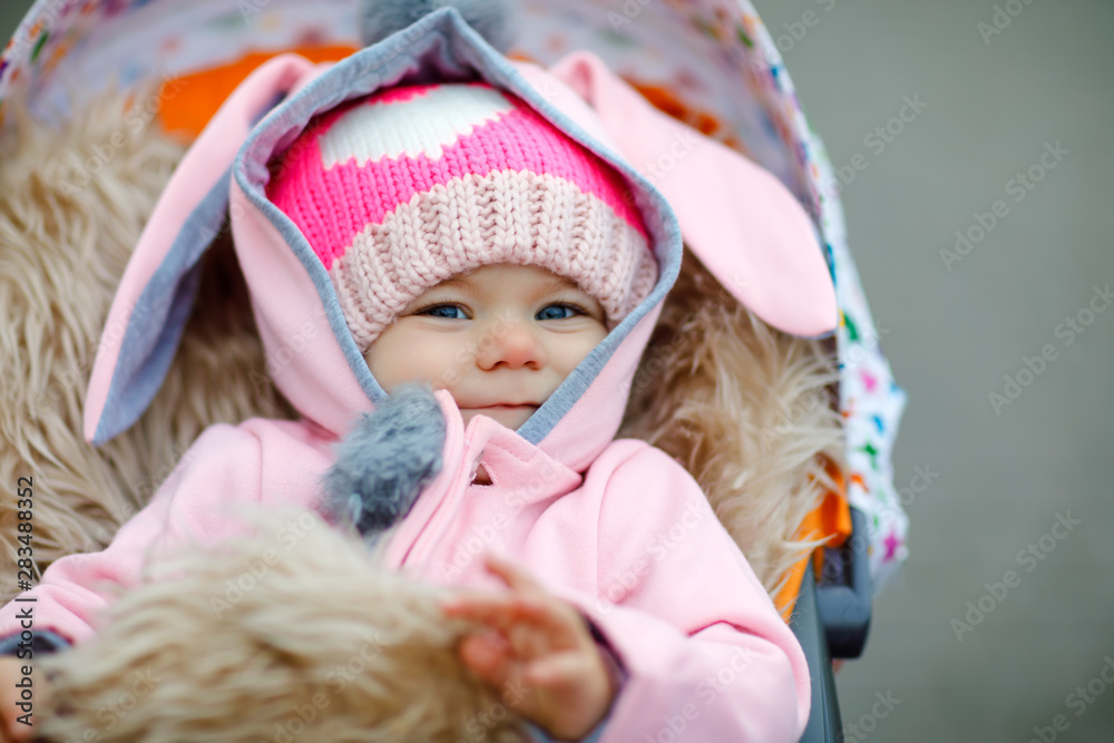 Cute little beautiful baby girl sitting in the pram or stroller on autumn day. Happy smiling child in warm clothes, fashion stylish baby coat. Healthy toddler going for walk on fresh air with parents Cute little beautiful baby girl sitting in the pram or stroller on autumn day. Happy smiling child in warm clothes, fashion stylish baby coat. Healthy toddler going for walk on fresh air with parents