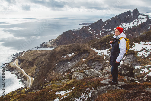 Man traveler hiking on Reinebringen mountain ridge in Norway lifestyle adventure traveling