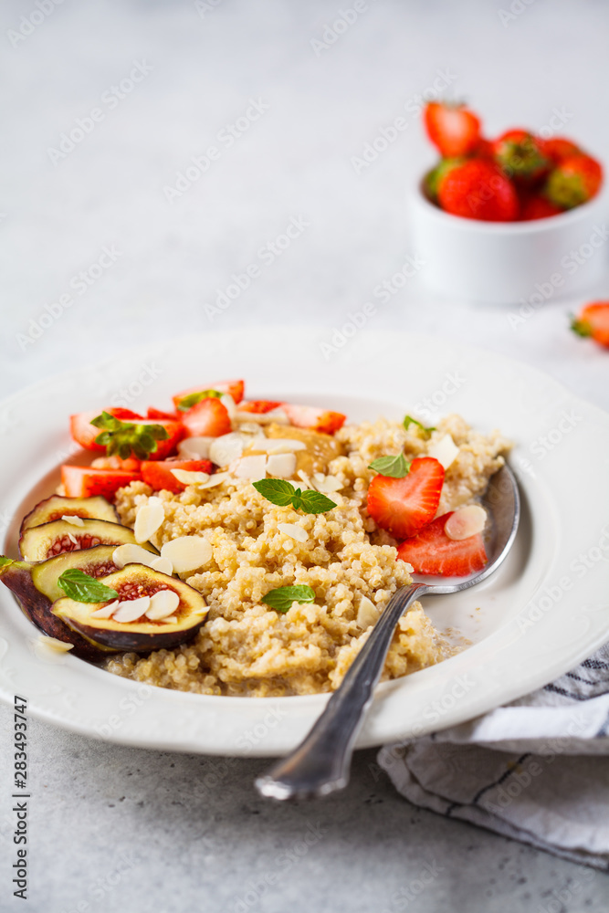 Quinoa breakfast porridge with strawberries and figs in white plate. Healthy breakfast concept.