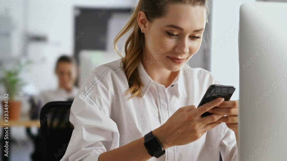 Young happy cute woman working in office using pc computer using mobile phone
