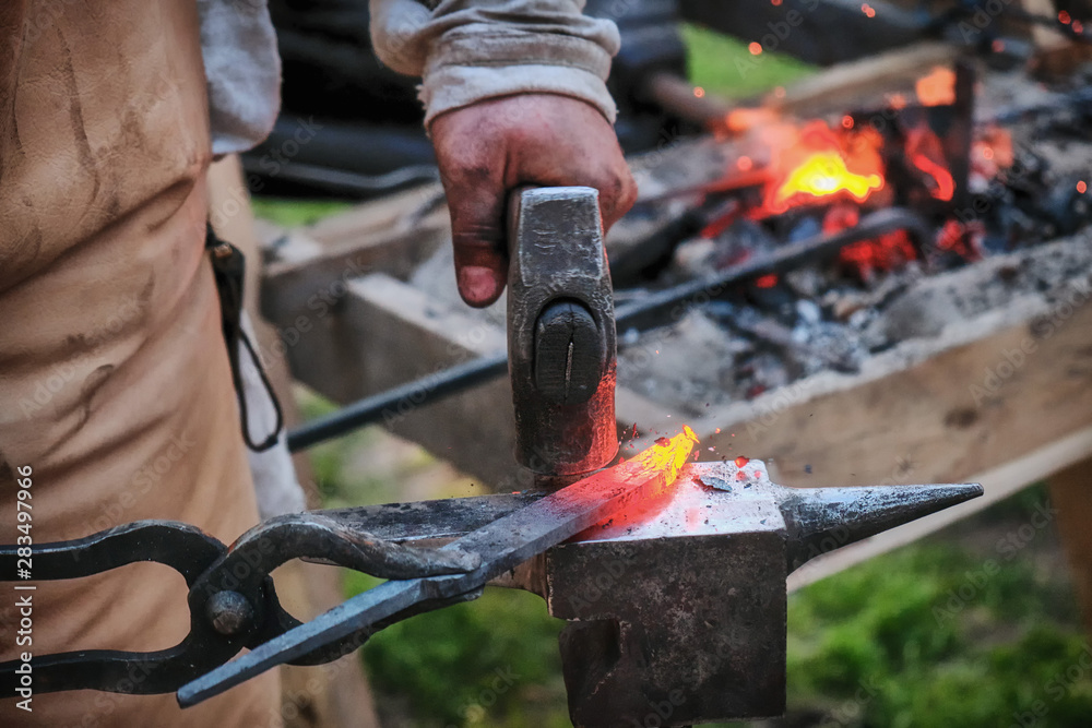 Twisting a red-hot billet is clamped in the grip. Blacksmith twists a hot rod on the anvil. Twisting a red-hot billet is clamped in the grip. Blacksmith twists a hot rod on the anvil.