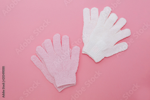 Woman exfoliating massage glove for shower on pink background.Gloves for use in the shower for massage and scrub. Beauty background with cosmetic products. Beauty, health and spa concept