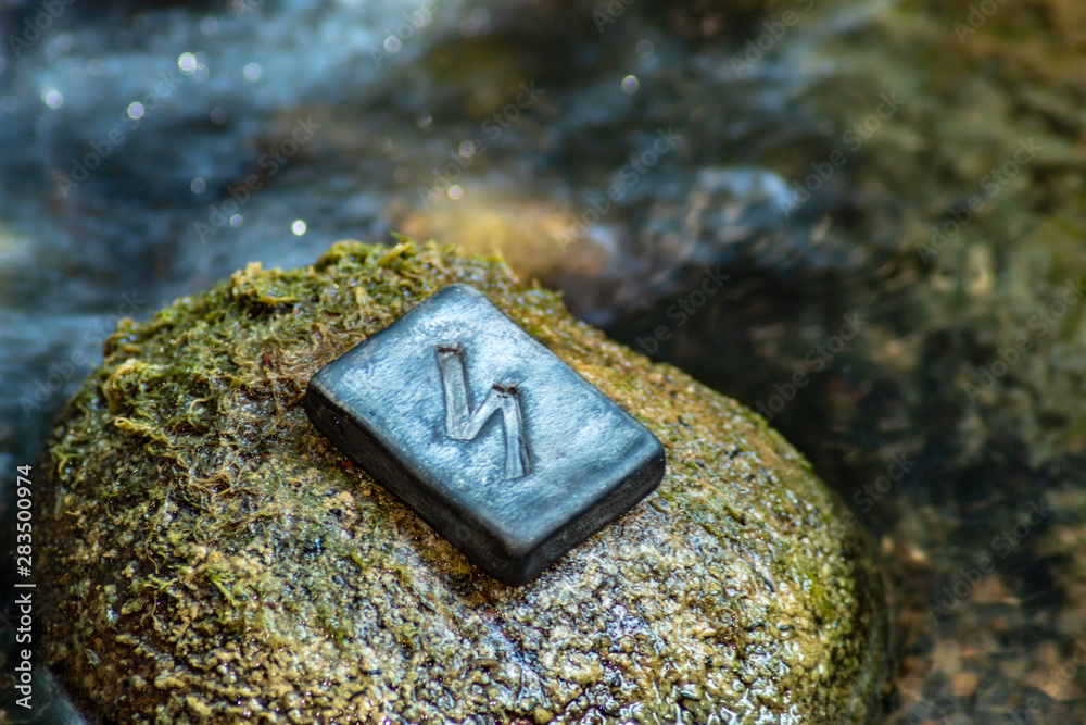 Norse rune Sowilo on the stone and the evening river background. The ...