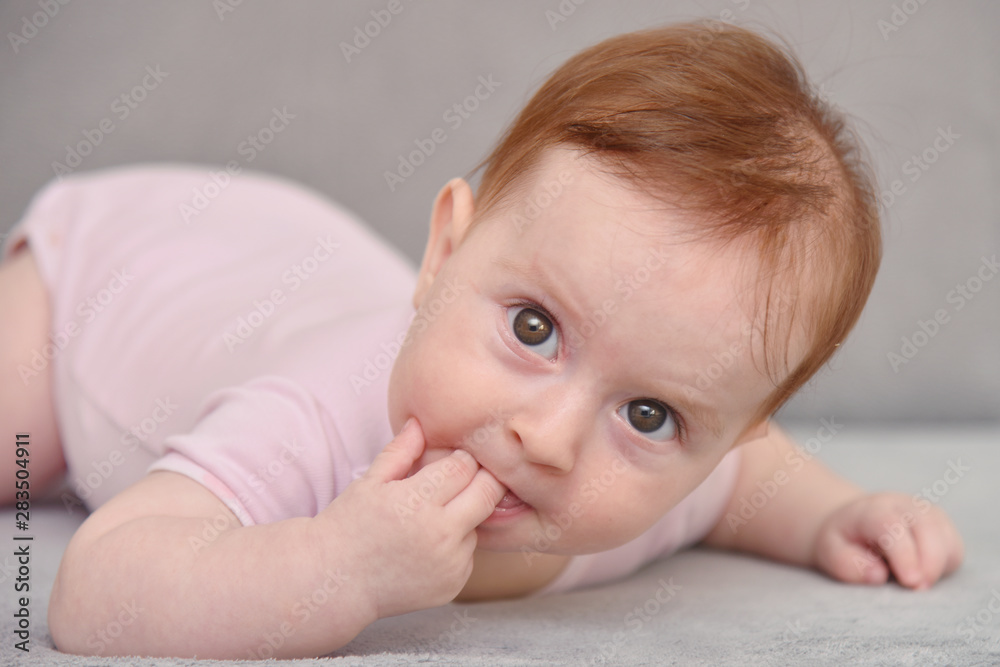 Happy Three Month Old Baby on White Background. Baby girl lying on her stomach on a grey background. Happy Three Month Old Baby on White Background. Baby girl lying on her stomach on a grey background.