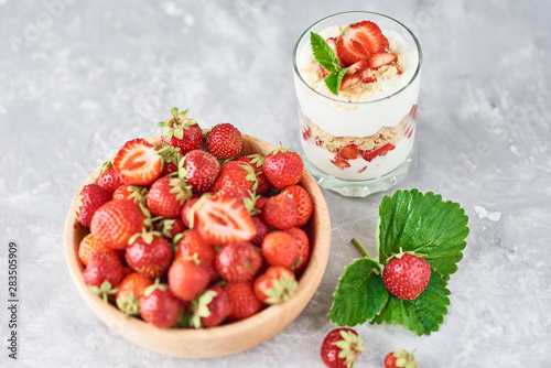 Strawberry granola or smoothie in glass and fresh berries in a wooden bowl. Healthy breakfast