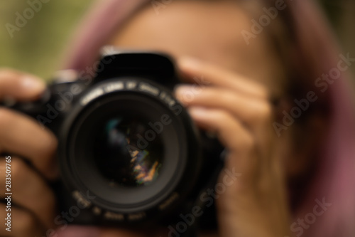 unfocused blurred concept female portrait of incognito photographer with black digital camera 