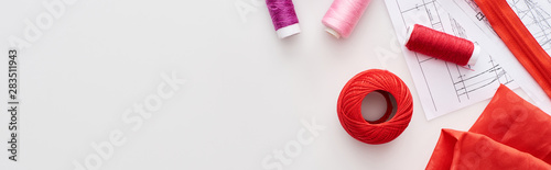 panoramic shot of colorful threads, knitting yarn ball, fabric, sewing patterns and zipper on white background