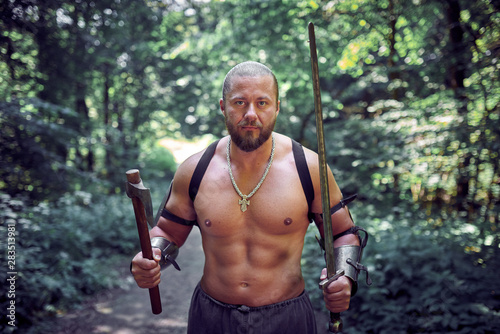 Muscular and strong man with ax and sword