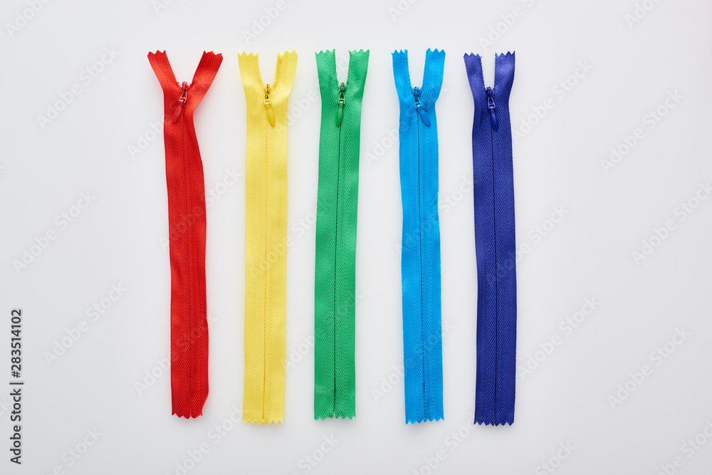 top view of bright and colorful zippers on white background top view of bright and colorful zippers on white background