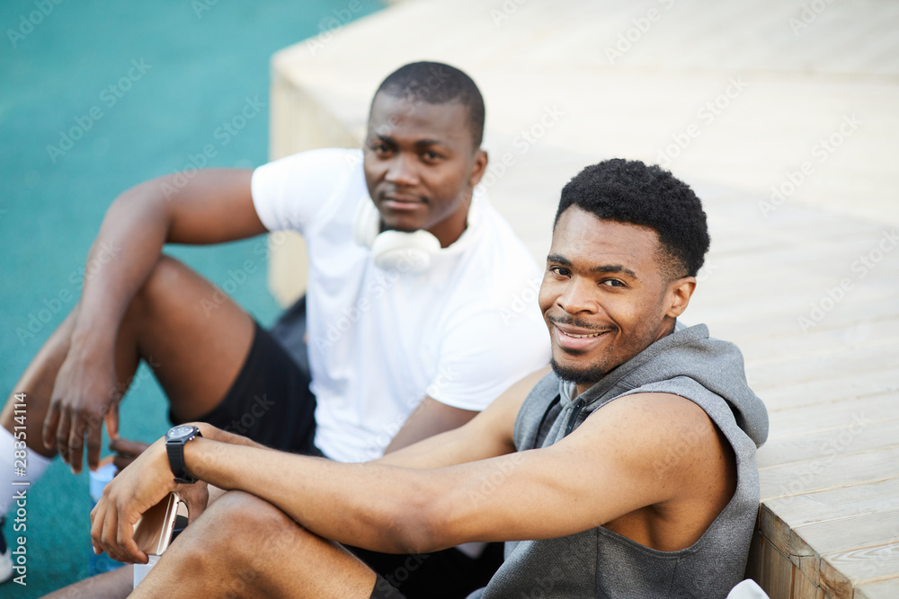 High angle portrait of two African-American guys smiling at camera while chilling in skate park outdoors, copy space High angle portrait of two African-American guys smiling at camera while chilling in skate park outdoors, copy space