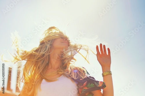 Attractive happy young woman in white t shirt flying hair enjoying her free time at sunset outdoor. Beauty blonde girl portrait at summer. Freedom lifestyle springtime concept. Sun glow on background. #283515950