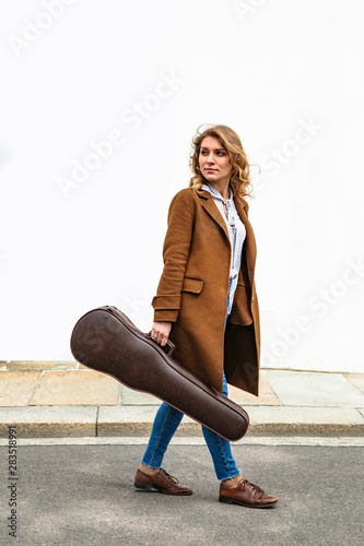 Girl with violin in hands on background of wall
