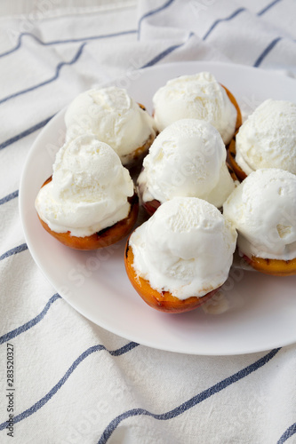 Homemade grilled peaches with vanilla ice cream on a white plate, low angle view. Close-up.