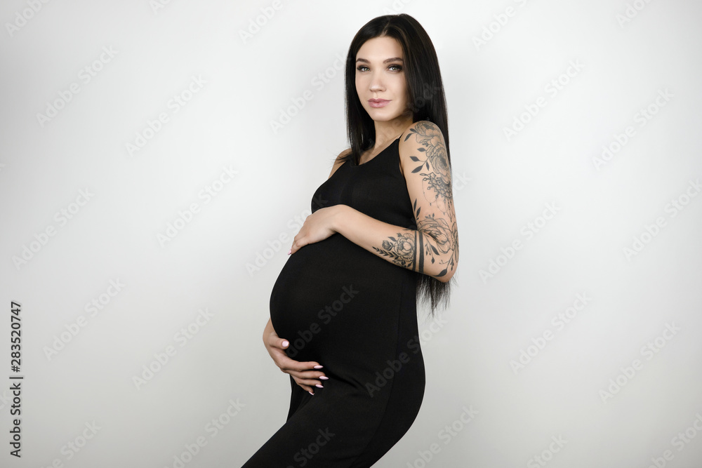 brunette young pregnant beautiful woman in long black trendy dress standing on isolated white background brunette young pregnant beautiful woman in long black trendy dress standing on isolated white background