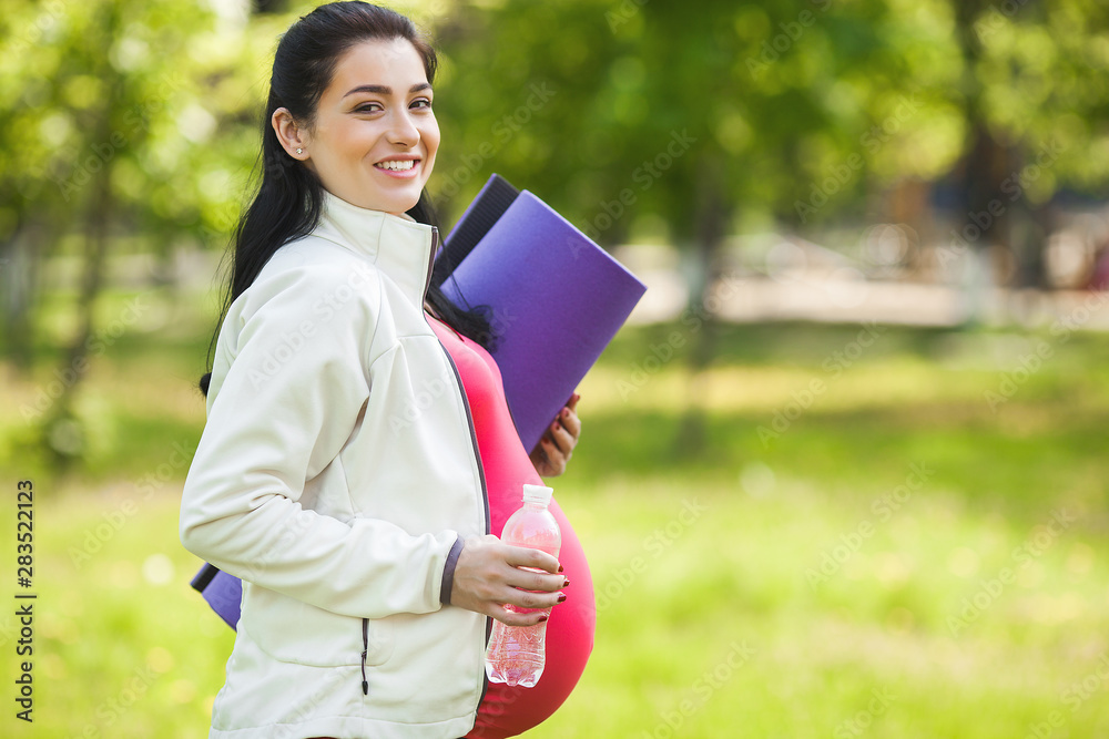Attractive young pregnant woman doing yoga exercises outdoors in the park. Expecting female having healthy and active lifestyle. Attractive young pregnant woman doing yoga exercises outdoors in the park. Expecting female having healthy and active lifestyle.