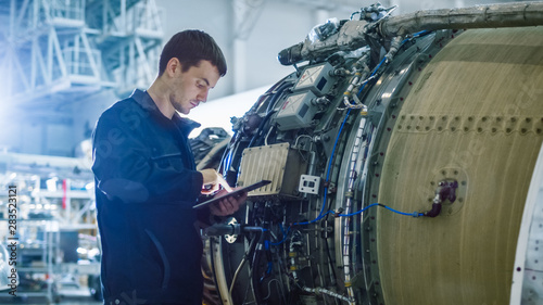 Aircraft Maintenance Mechanic Inspecting and Working on Airplane Jet Engine in Hangar photo