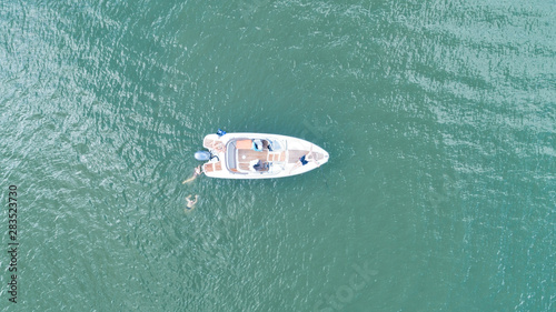 Motorboat at the baltic sea. Aerial view of floating boat with people in transparent blue water at sunny day. Summer landscape. Top view from drone.