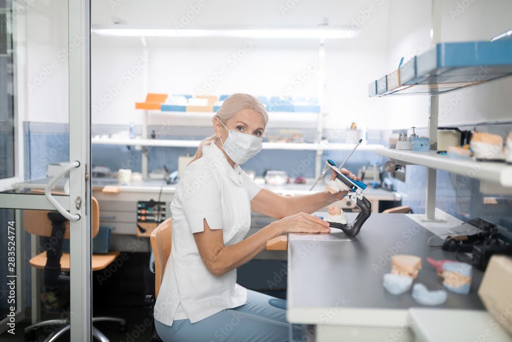 Serious dental technician looking at her colleague. Serious dental technician looking at her colleague.