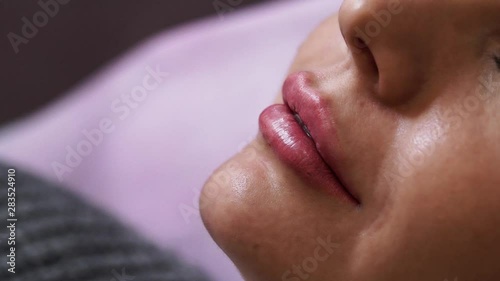 The doctor makes an injection to the patient in the lips