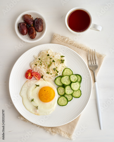 Healthy breakfast - fried egg with cherry tomatoes and cucumber on light white background, fodmap dash diet, gluten free, top view closeup