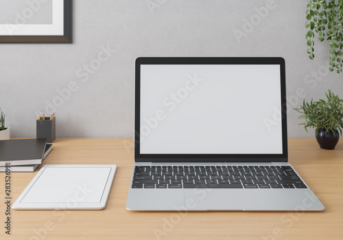 Laptop and tablet on the table in interior. Mockup white screen.