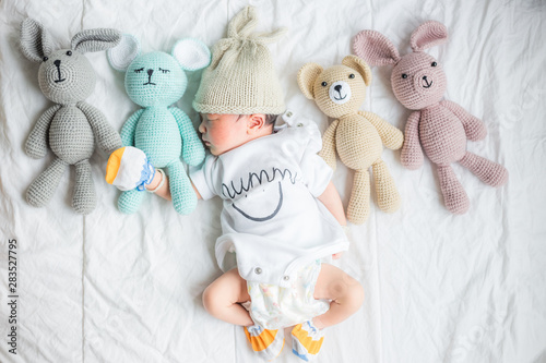 Sleepin of infant baby boy with many doll on white blanket
