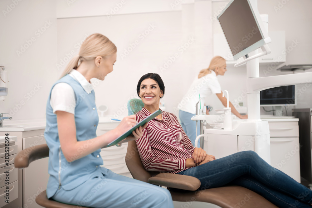 Obraz premium Dentists assistant asking their patient different questions.
