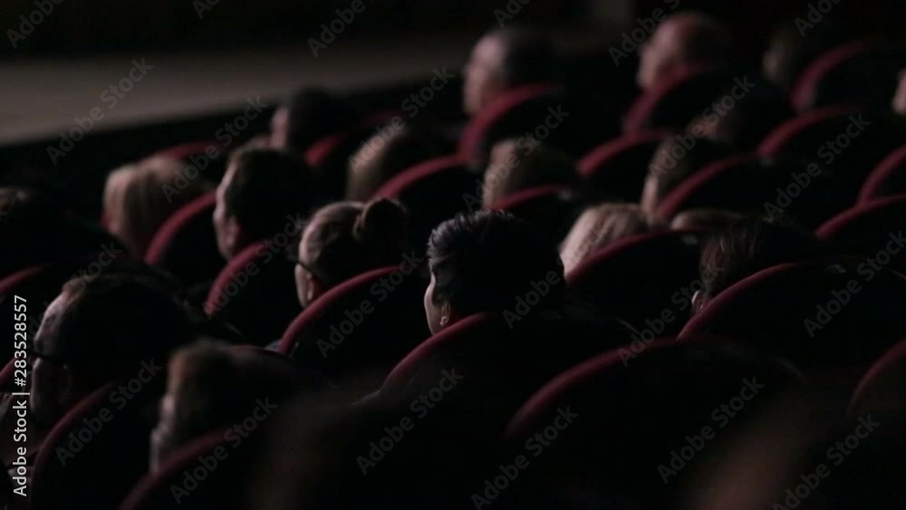 Spectators people in a dark movie theater watching a movie