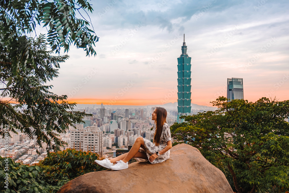 Obraz premium Traveler women and sunset with view of skyline of Taipei cityscape Taipei 101 building of Taipei financial city ,Taiwan