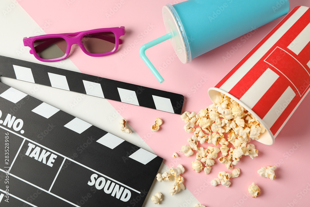 Bucket with popcorn, clapperboard, drink and 3d glasses on two tone background