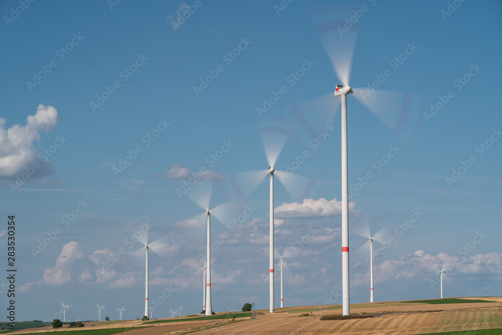 Wind turbines on the fields under a blue sky with some clouds