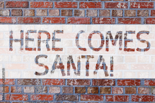 Handwriting text writing Here Comes Santa. Concept meaning Christmas song written and performed by Gene Autry Brick Wall art like Graffiti motivational call written on the wall