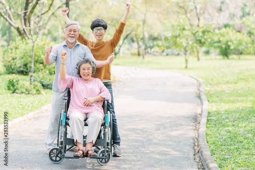 Happy family with senior woman in wheelchair in the park