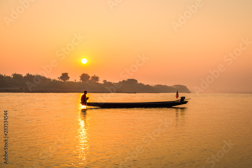 Fishermen in the boat on sunrise background © songdech17