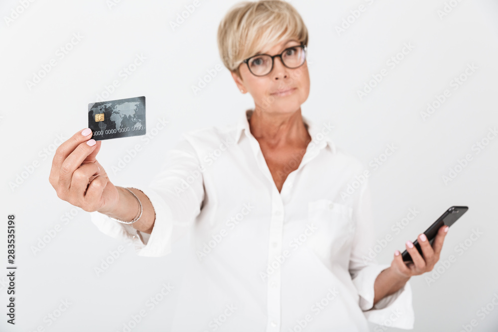 Portrait of attractive adult woman with short blond hair holding cellphone and credit card Portrait of attractive adult woman with short blond hair holding cellphone and credit card