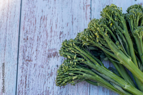 Bunch of fresh broccolini on a wooden table background. Healthy eating. Cooking ingredient. Hybrid of broccoli and chinese broccoli photo