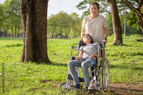 Sick child girl with cerebral palsy in wheelchair outdoor park or daughter suffering from seizures,illness with epilepsy,asian mother or caregiver care of girl patient,brain,intellectual disability 