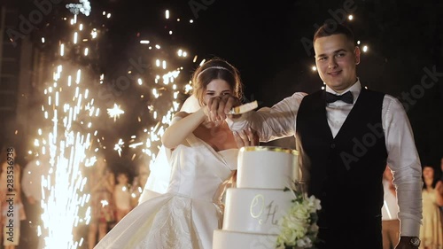 Bride and groom cut the cake and feed each other and laugh on their wedding day