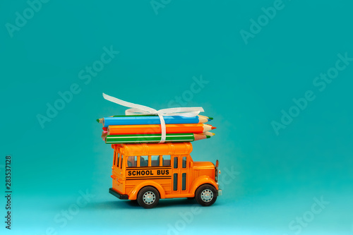 Yellow retro school bus with pencils on roof on blue background. Concept education and back to school.