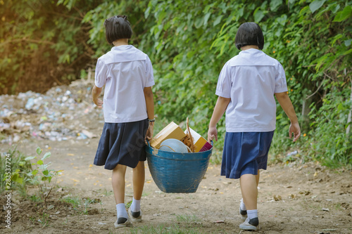 Female Students help to remove rubbish from the classroom to pile waste © JinnaritT