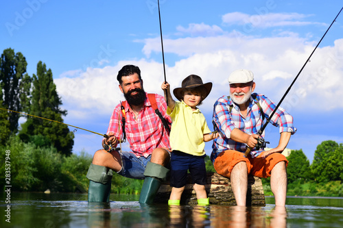 Fototapeta Grandfather, father and son are fly fishing on river.