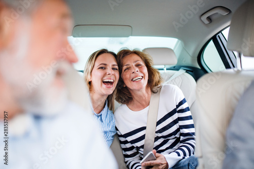 Cheerful adults sitting in car, going on a trip.