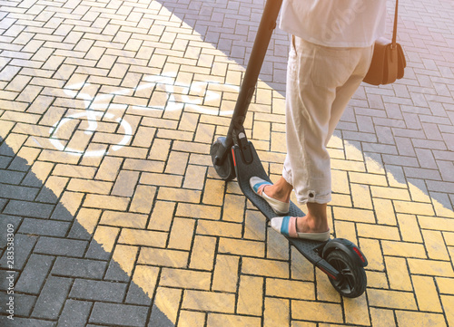 Woman riding an electric scooter on cycle path, view of legs.