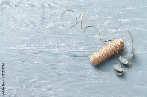 Natural twine and dry eucalyptus leaves on wooden background. Flat lay. Copy space