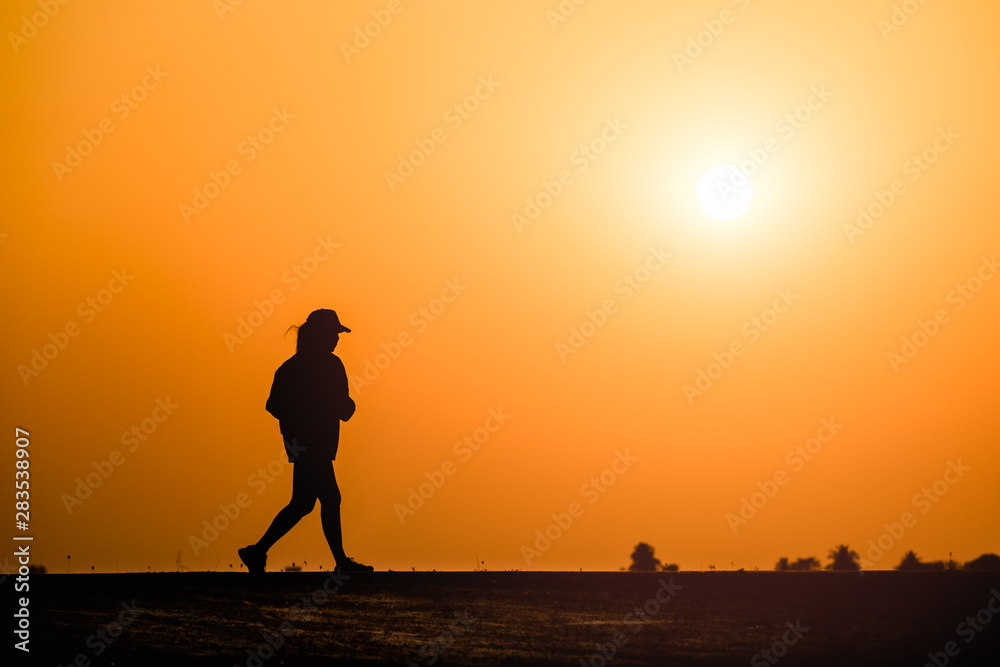 Silhouette woman running on sunset background